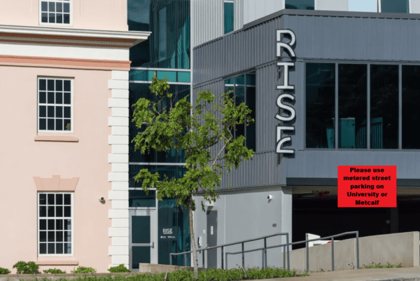 Image of the Walter Dods Jr. RISE Building entrance. A red box overlays the image. It says to park at the meters on University or Metcalf.